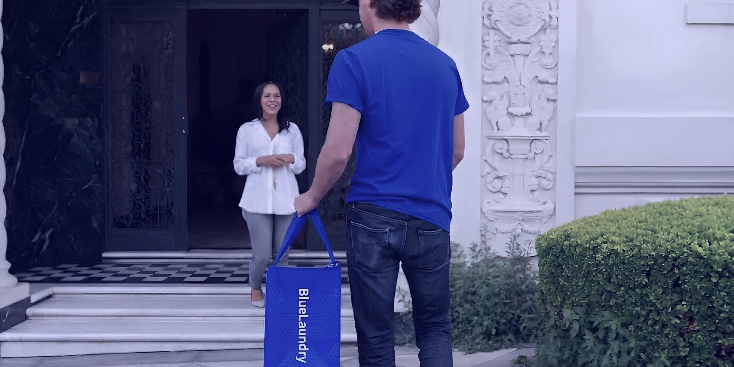Un livreur BlueLaundry remet un sac de linge à une cliente